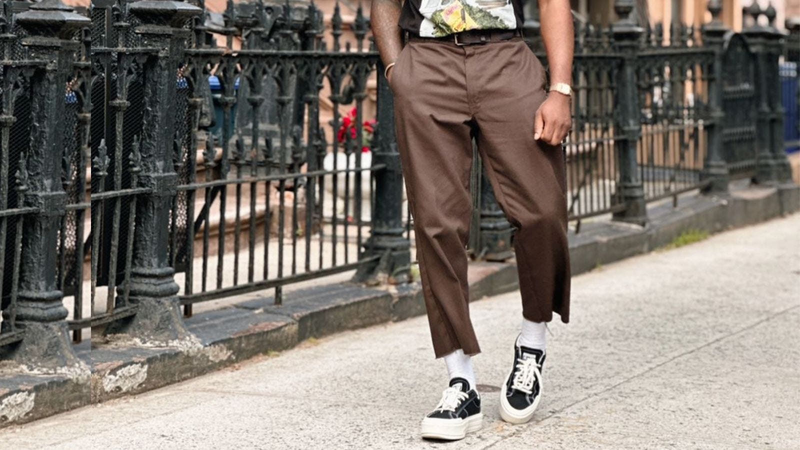 image of a man from the waist down wearing brown pants with tall white socks and black and white sneakers